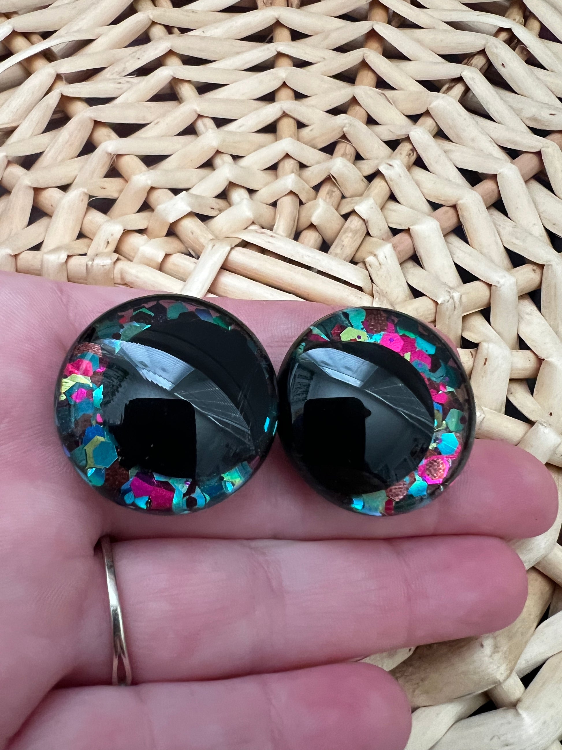 Hand painted safety eyes that feature large kawaii style black pupils with a vibrant shimmery jewel toned iris with purple, pink, and blue glitter throughout. Eyes are for crochet and knit amigurumi 