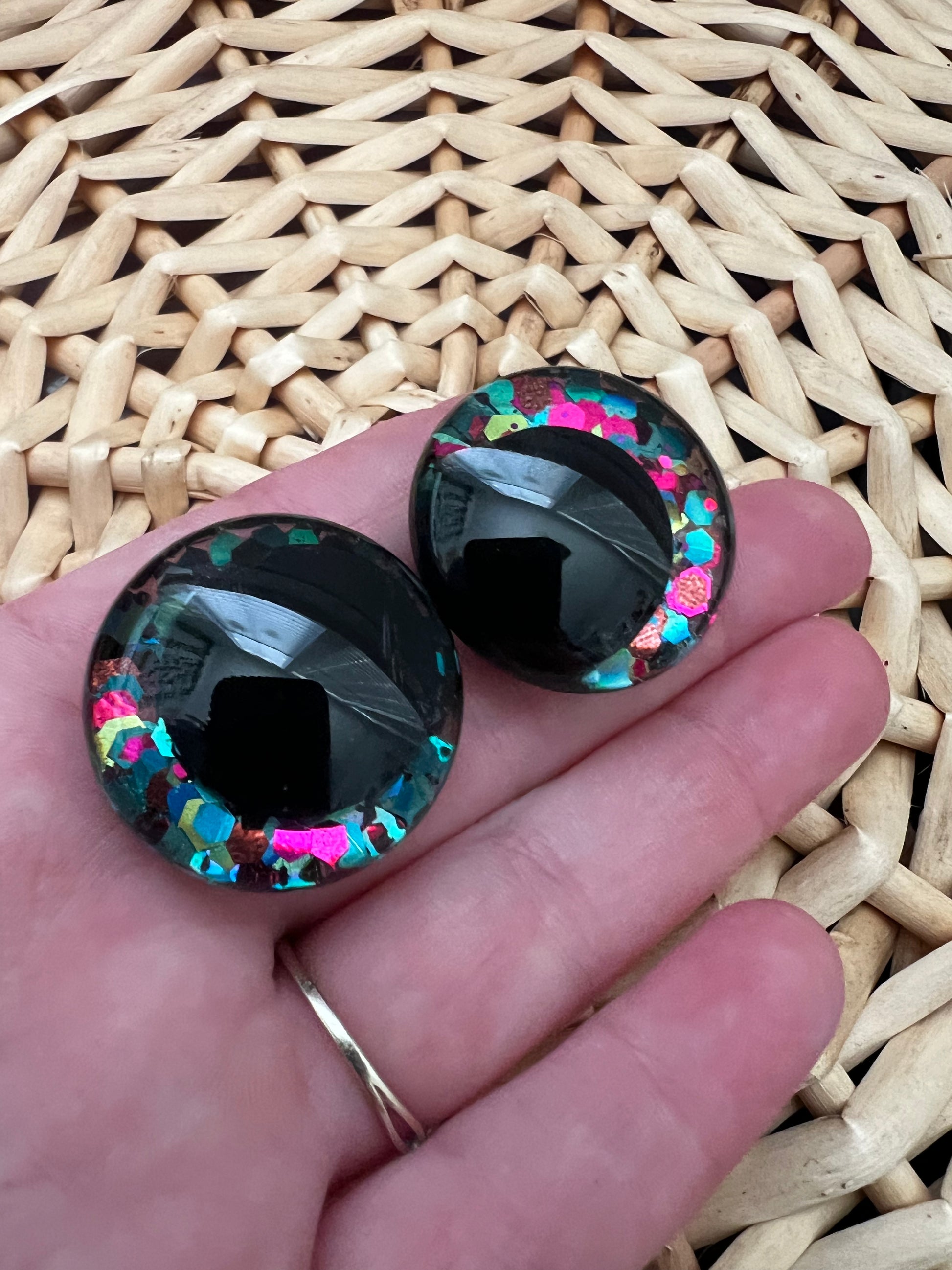 Hand painted safety eyes that feature large kawaii style black pupils with a vibrant shimmery jewel toned iris with purple, pink, and blue glitter throughout. Eyes are for crochet and knit amigurumi 